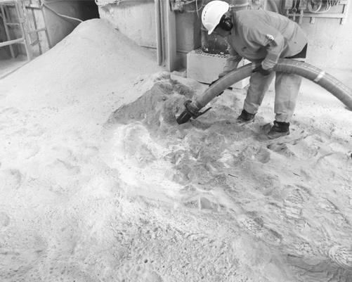 Homme aspirant du sable ciment avec tuyau